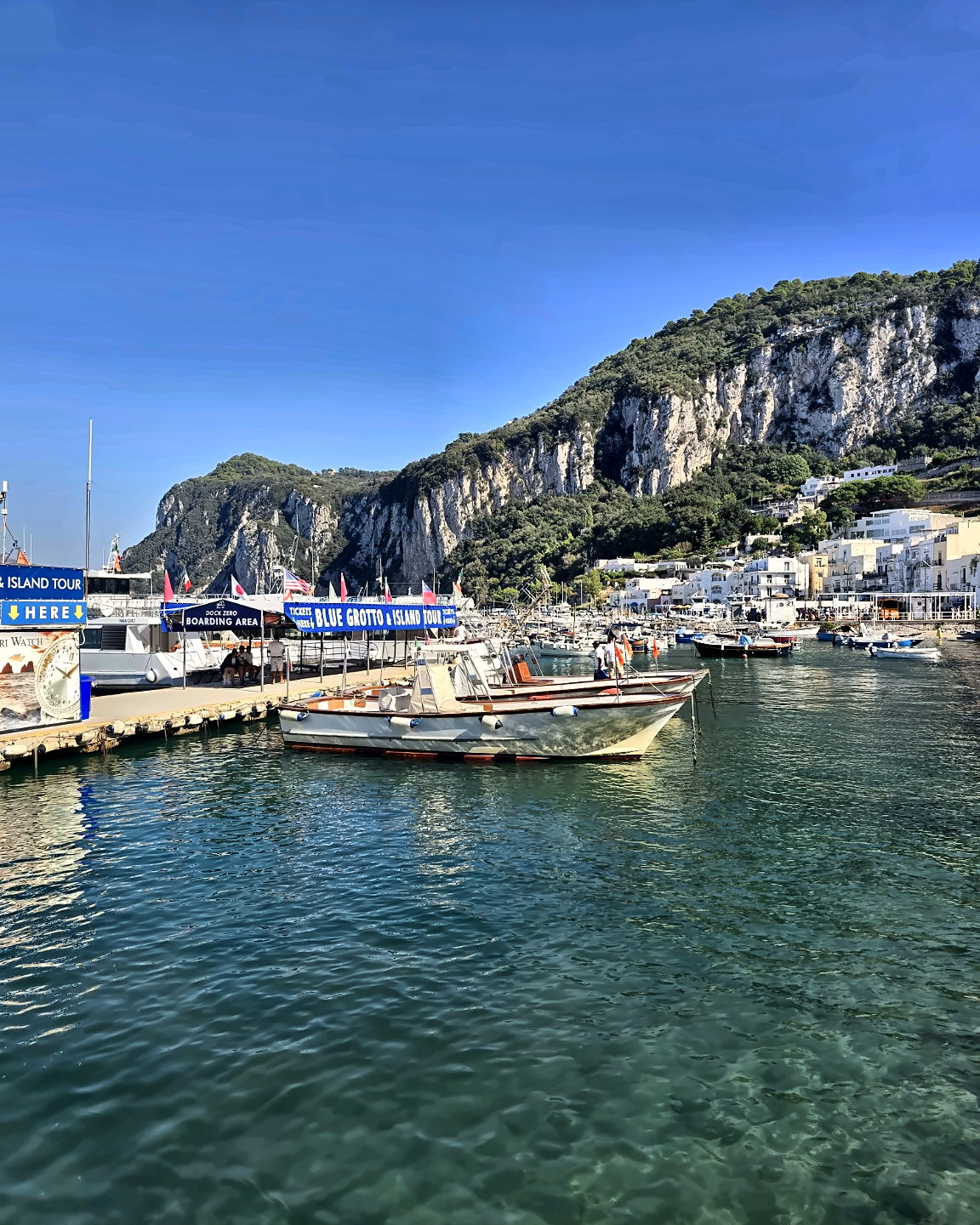 Marina Grande in Capri with a ferry, cliffs and blue sea