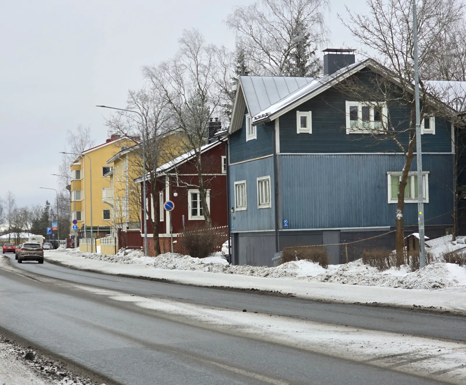 Blue, red and yellow wooden houses along a snowy street in Pispala, Tampere