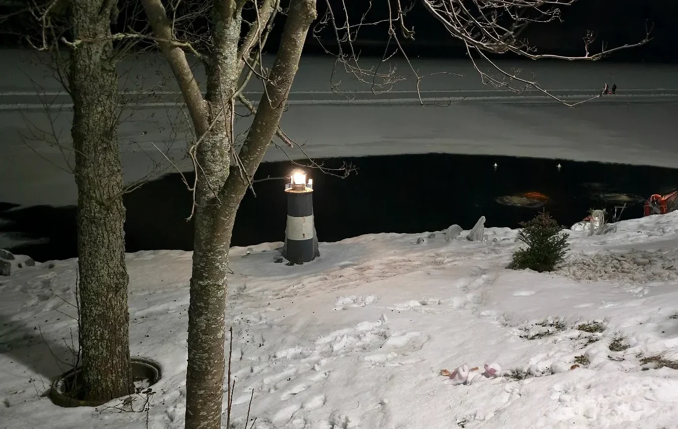 Ice swimming hole beside the frozen lake at Kaupinoja Sauna in Tampere at night