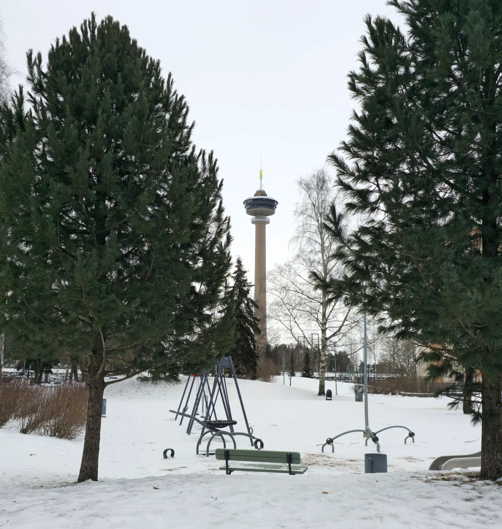 Näsinneula Observation Tower framed by pine trees in snowy Tampere