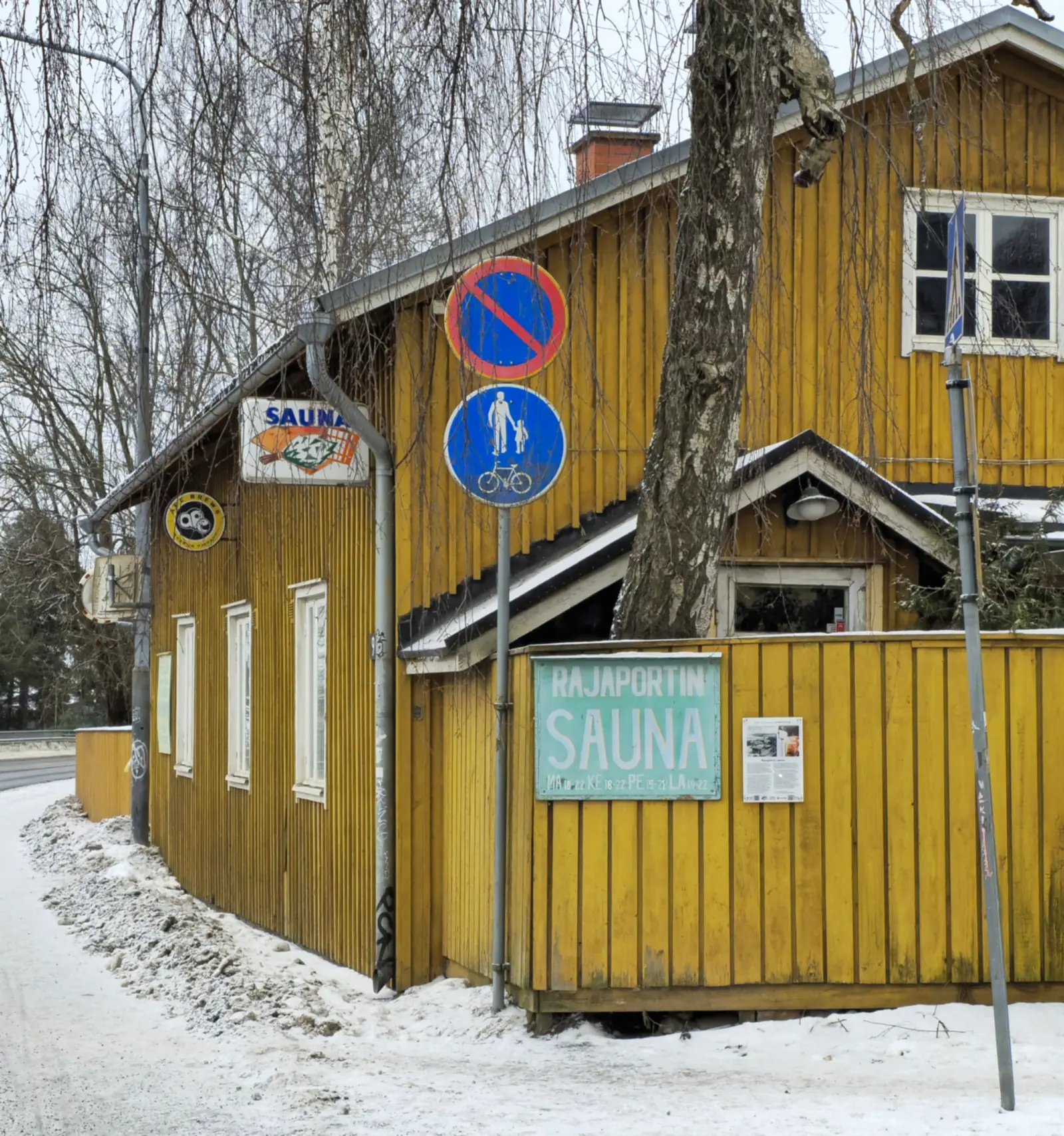 Yellow wooden Rajaportti Sauna building in snowy Pispala, Tampere