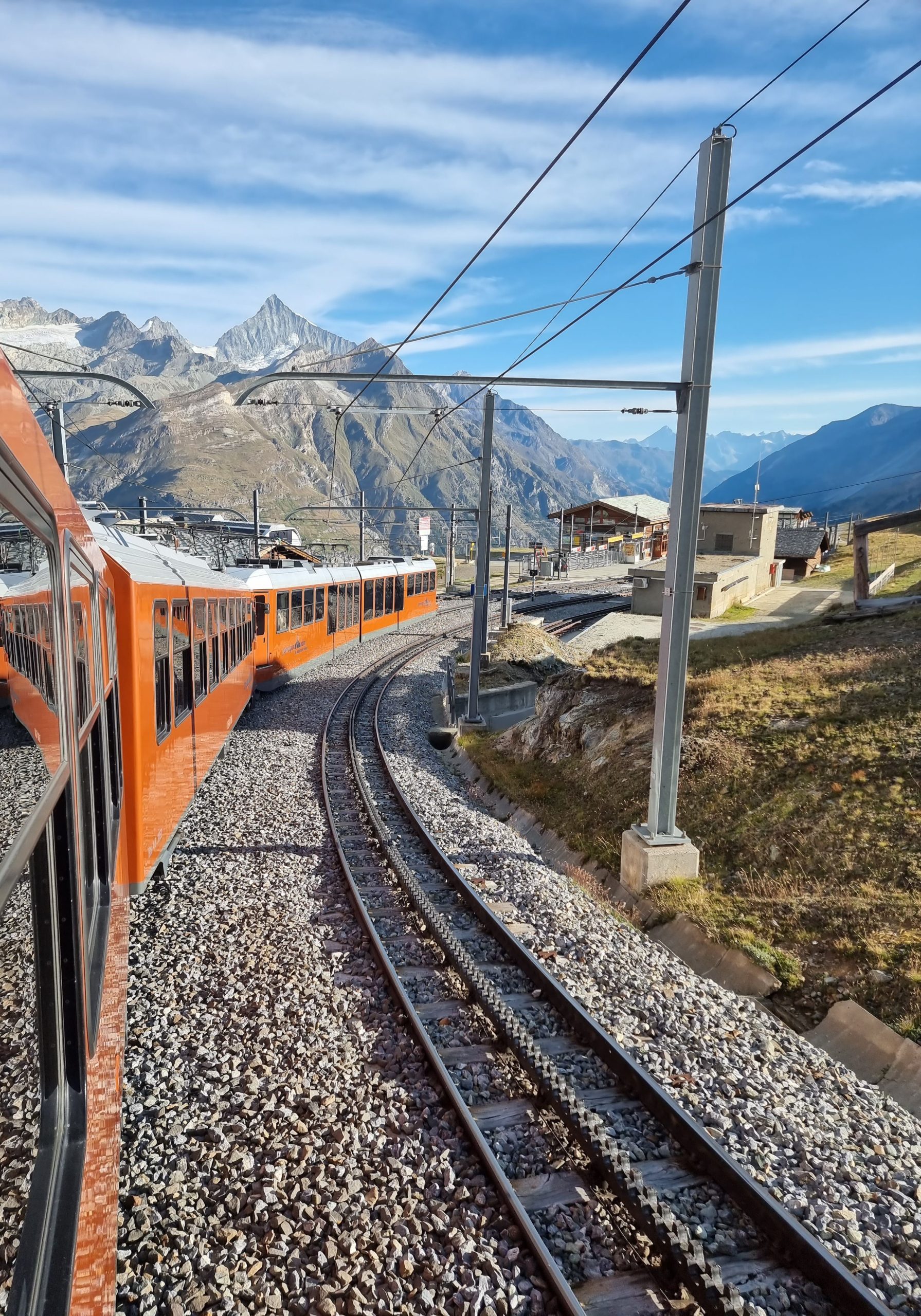 Orange train travelling through the Swiss Alps near Zermatt
