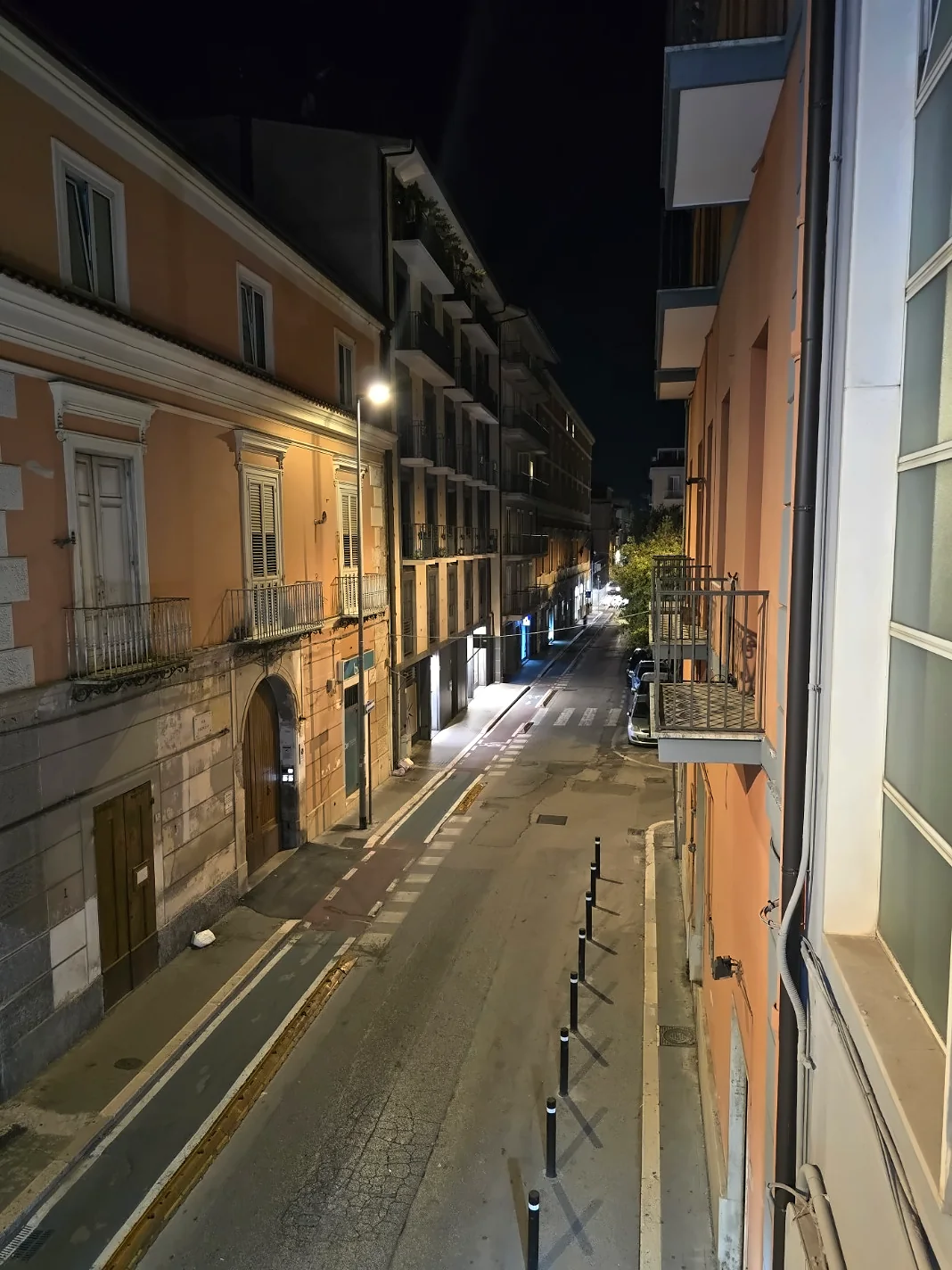 Night view from the balcony of Sweet Central Hotel in Caserta towards a narrow street and illuminated façades.