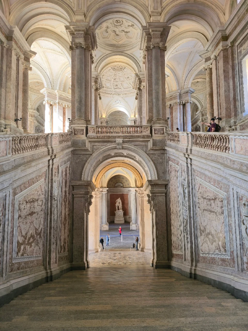 Monumental marble staircase of the Reggia di Caserta, with arches and a colonnade.