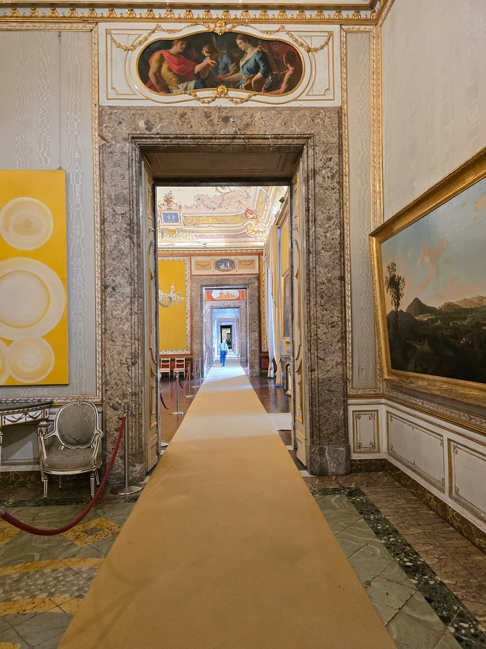Sequence of connected royal rooms in the Reggia di Caserta, framed by marble doorways.