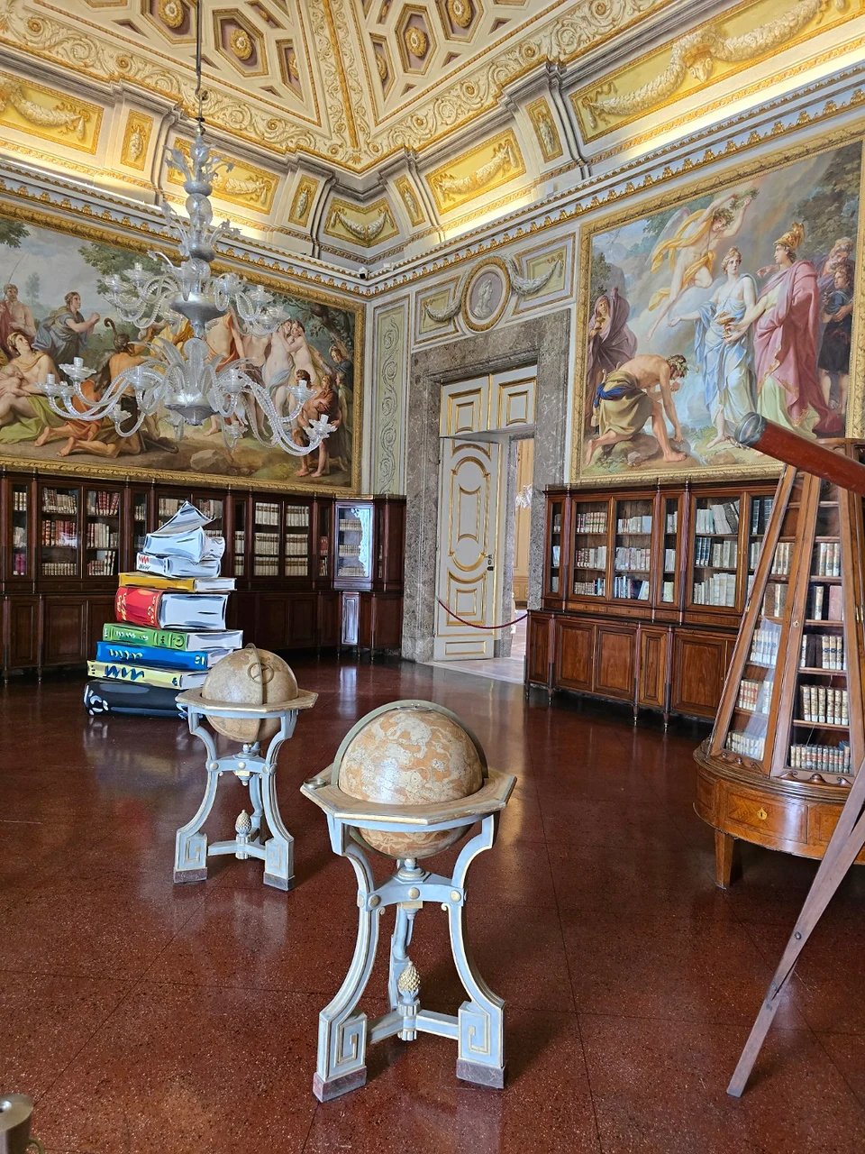 Library in the Reggia di Caserta with two globes, wooden bookcases and painted walls.