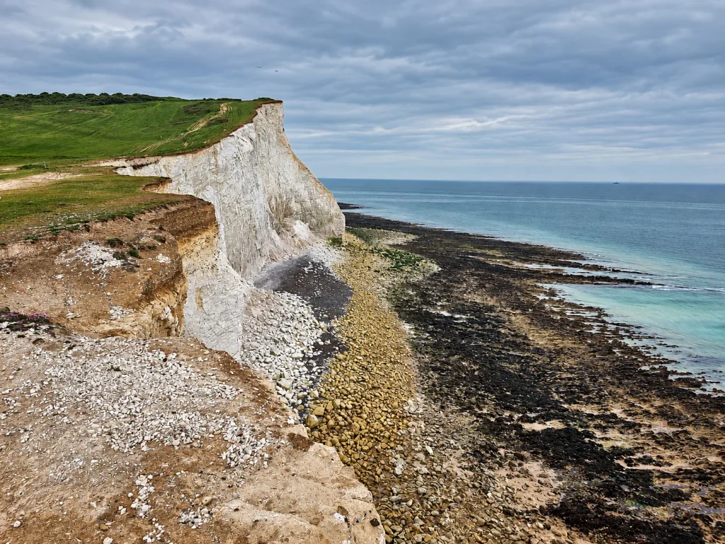 Edge of a white chalk cliff at Seven Sisters above the rocky shore